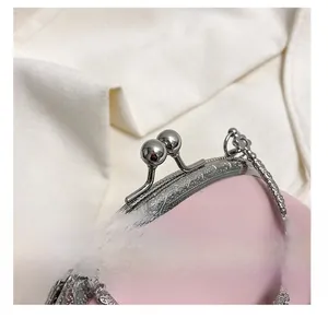 Detailed close-up of vintage engraved silver metal clasp and pink leather bag handle