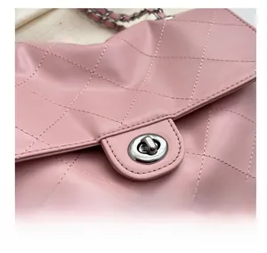 Détail du sac à bandoulière en cuir matelassé rose avec fermoir rotatif argenté et chaîne