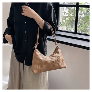 Detail of beige pleated shoulder bag featuring elegant side knot and soft texture