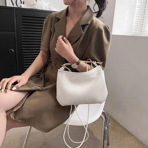 White pleated crossbody bag with a golden metal handle and slim shoulder strap