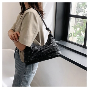 Detail of black pleated shoulder bag featuring soft texture and stylish knot strap detail