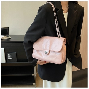 Détail de la texture matelassée rose et du fermoir argenté du sac bandoulière à chaîne
