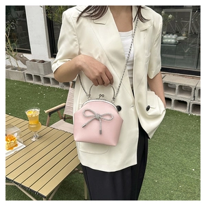 Close-up of pink shell-shaped crossbody bag featuring a sparkling rhinestone bow detail