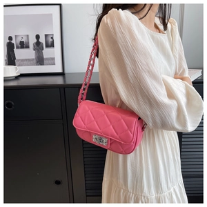 Dettaglio della borsa rosa trapuntata con catena argento su modella in abito bianco