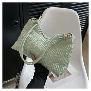 Close-up of mint green pleated leather bag with gold rings on a white chair