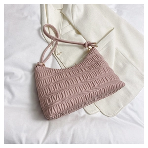 Close-up of pink pleated shoulder bag texture and knotted strap detail on white fabric