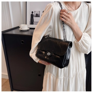 Détail du sac bandoulière matelassé noir avec fermoir argenté et bandoulière chaîne