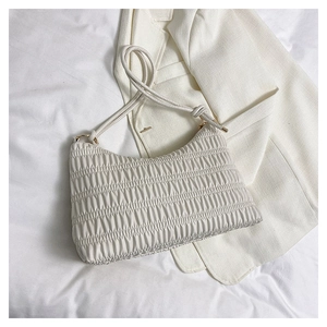 Detailed close-up of white pleated crossbody bag featuring soft leather texture and knots