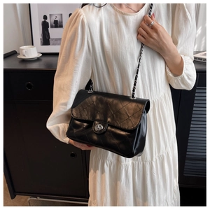 Détail d'un sac bandoulière matelassé noir avec fermoir tournant argenté et chaîne