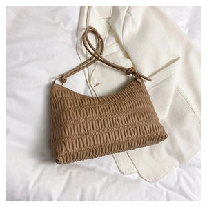 Detail of a brown pleated tote bag with golden metal rings and leather strap