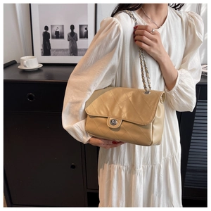 Détail du sac matelassé beige avec fermoir argenté et bandoulière en chaîne chic