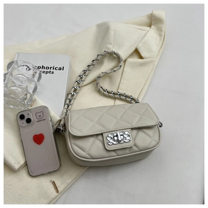 Dettaglio borsa a tracolla trapuntata beige con chiusura a scatto e catena in metallo lucido