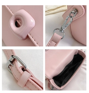 Detail view of pink crossbody bag showing buckles, silver hooks, and inner lining texture