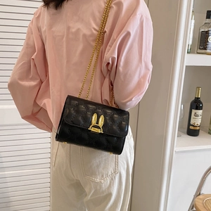 Quilted black crossbody chain bag with golden bunny ears clasp shown in a lifestyle setting