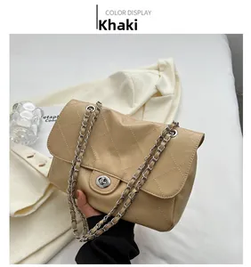 Détail du sac matelassé kaki avec fermoir argenté sur fond de blazer blanc élégant