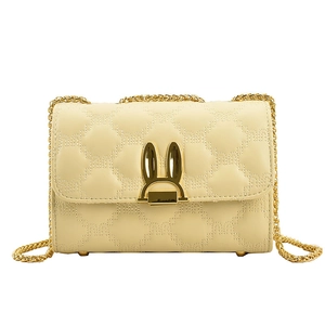 Cream quilted chain shoulder bag with golden rabbit ear clasp on white background