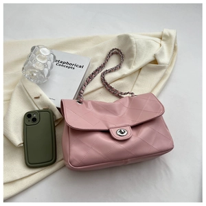 Détail d'un sac matelassé rose avec bandoulière en chaîne argentée et fermoir rotatif