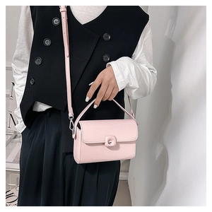 Detail of pink leather crossbody bag showing turn-lock closure and detachable strap