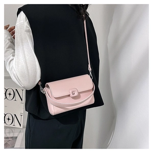 Detail view of pink rectangular crossbody bag with fine leather texture and flap buckle
