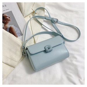 Macro detail of light blue leather handbag with square buckle on white fabric background