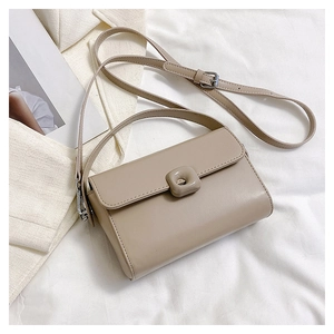 Top-down view of a khaki leather crossbody bag with a metal buckle on a white cloth background