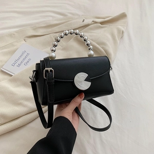 Mini black crossbody bag with silver beaded handle and pearl accents on knit fabric