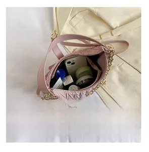 Interno spazioso di una borsa rosa a pieghe con oggetti quotidiani e catena dorata