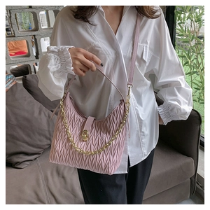 Dettaglio della borsa a mano rosa increspata con catena d'oro e tracolla su una modella