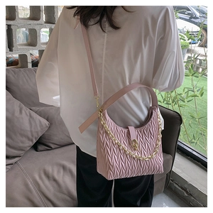Borsa a mano rosa matelassé con catena dorata indossata da una modella donna