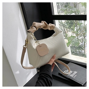 Détail du sac plissé blanc cassé avec poignée nuage kaki et finitions dorées chic