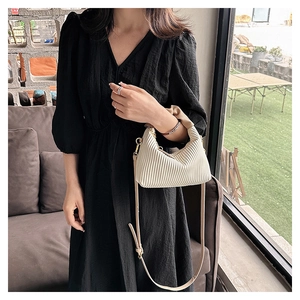 Détail d'un sac à main plissé blanc cassé avec textures verticales et bandoulière