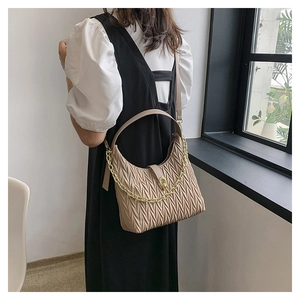 Dettaglio della borsa a mezzaluna arricciata con catena dorata in tonalità beige