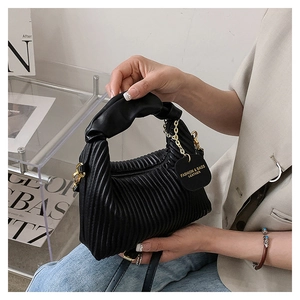 Gros plan du sac à main plissé en cuir noir avec poignée nouée et détail de chaîne dorée
