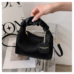 Détail du sac plissé en similicuir noir avec ferrures dorées et étiquette de mode