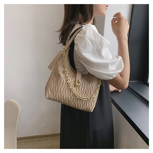 Dettaglio borsa hobo beige plissettata con catena dorata indossata dal modello