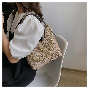 Dettaglio della borsa a mano pieghettata beige con catena in metallo dorato e chiusura