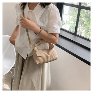Détail du sac à main plissé beige avec poignée froncée et bandoulière en cuir amovible