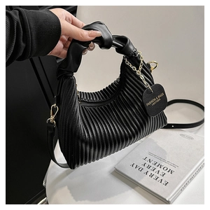 Détail du sac plissé noir avec poignée nouée et chaîne décorative à maillons dorés