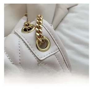 Detailed close-up of white quilted leather texture and gold chain hardware on handbag