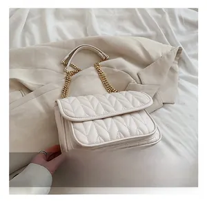 Detail shot of the cream quilted crossbody bag featuring a luxury gold chain strap