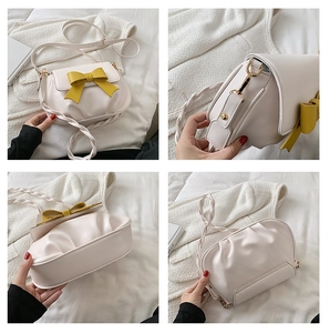 Dettaglio della borsa a tracolla bianco crema con fiocco giallo senape e oro