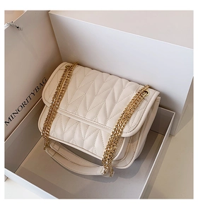Close-up of white V-quilted flap bag with gold chain straps in a premium gift box