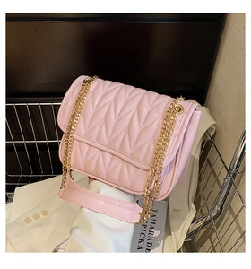 Detailed view of pink quilted chain bag with V-shaped texture and gold metal shoulder strap