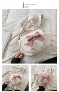 Dettaglio di una borsa a tracolla bianca e rosa con un grande fiocco e tracolla intrecciata