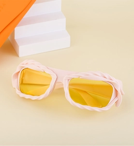 Detail of pink Y2K sunglasses with woven texture frame and yellow lenses on a geometric stand