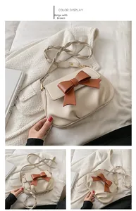 Dettaglio della borsa a tracolla in pelle beige con fiocco marrone e cinturino