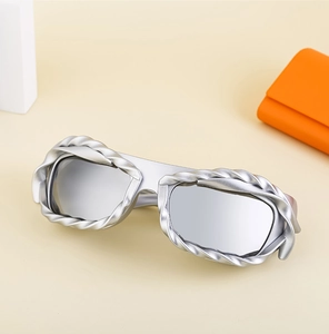 Detail of Y2K sunglasses with silver braided textured frame and orange storage case