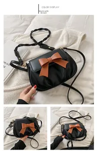 Dettaglio borsa a tracolla vintage in pelle nera con grande fiocco marrone e pieghe