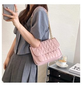 Detailed close-up of pink V-quilted leather crossbody bag with golden chain strap