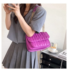Detail view of purple quilted chain bag with V-shaped stitching and golden metal strap